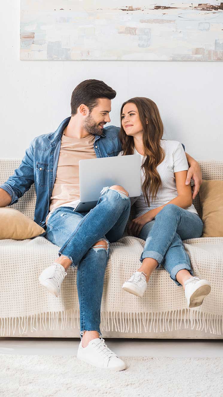 a couple sit on a couch and go over a home inventory list